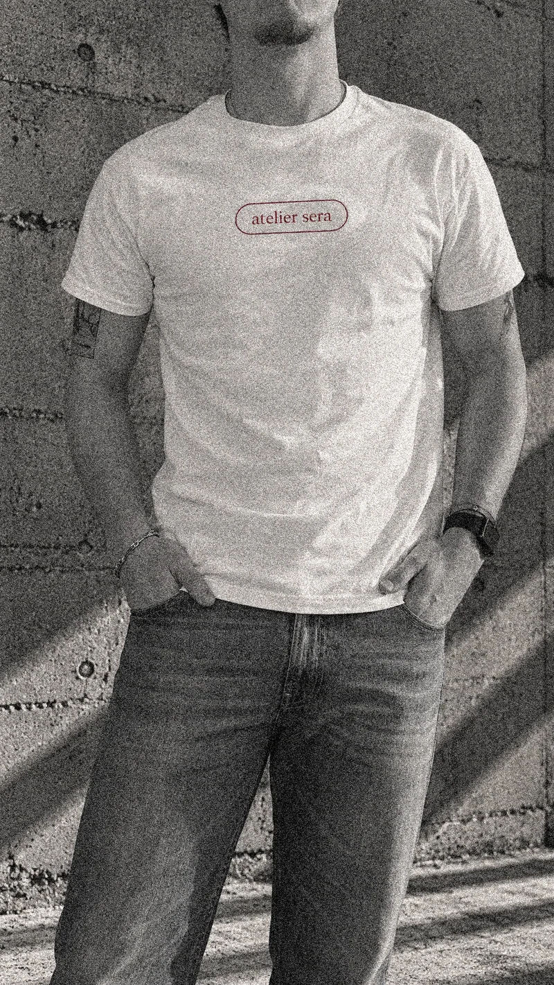 Atelier Sera logo tee worn from the front, showing the burgundy pill-shaped chest logo.